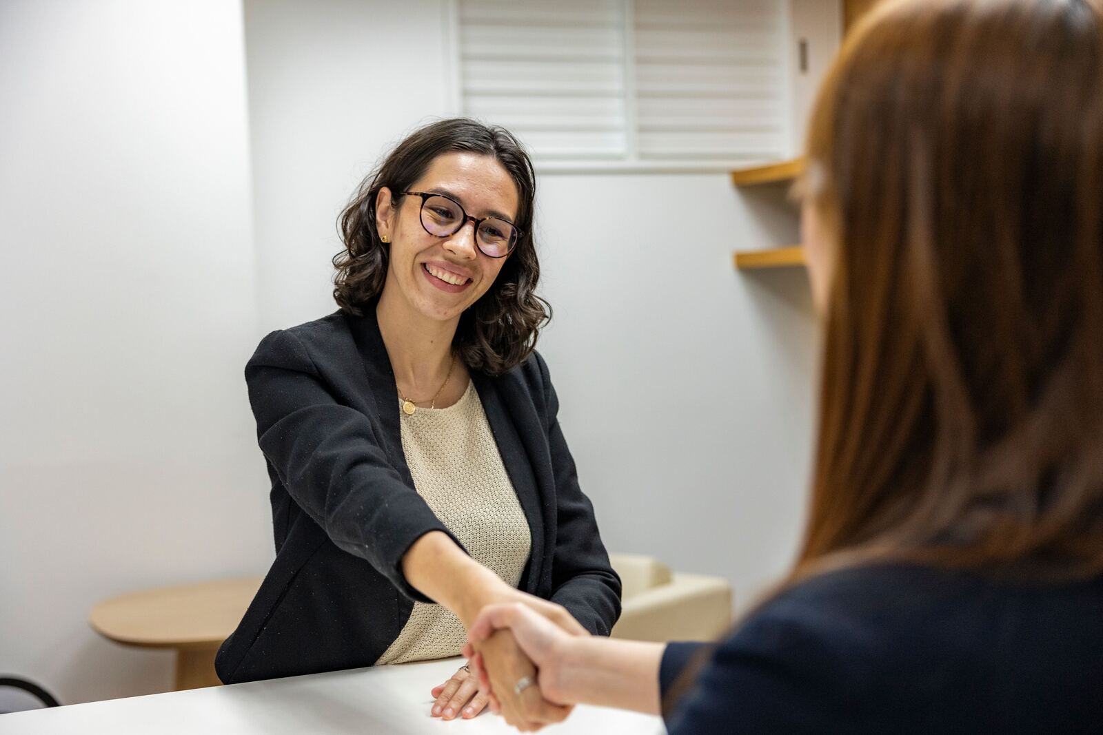 Global Business Consulting and Training 117 Two women shaking hands across a desk at a job interview